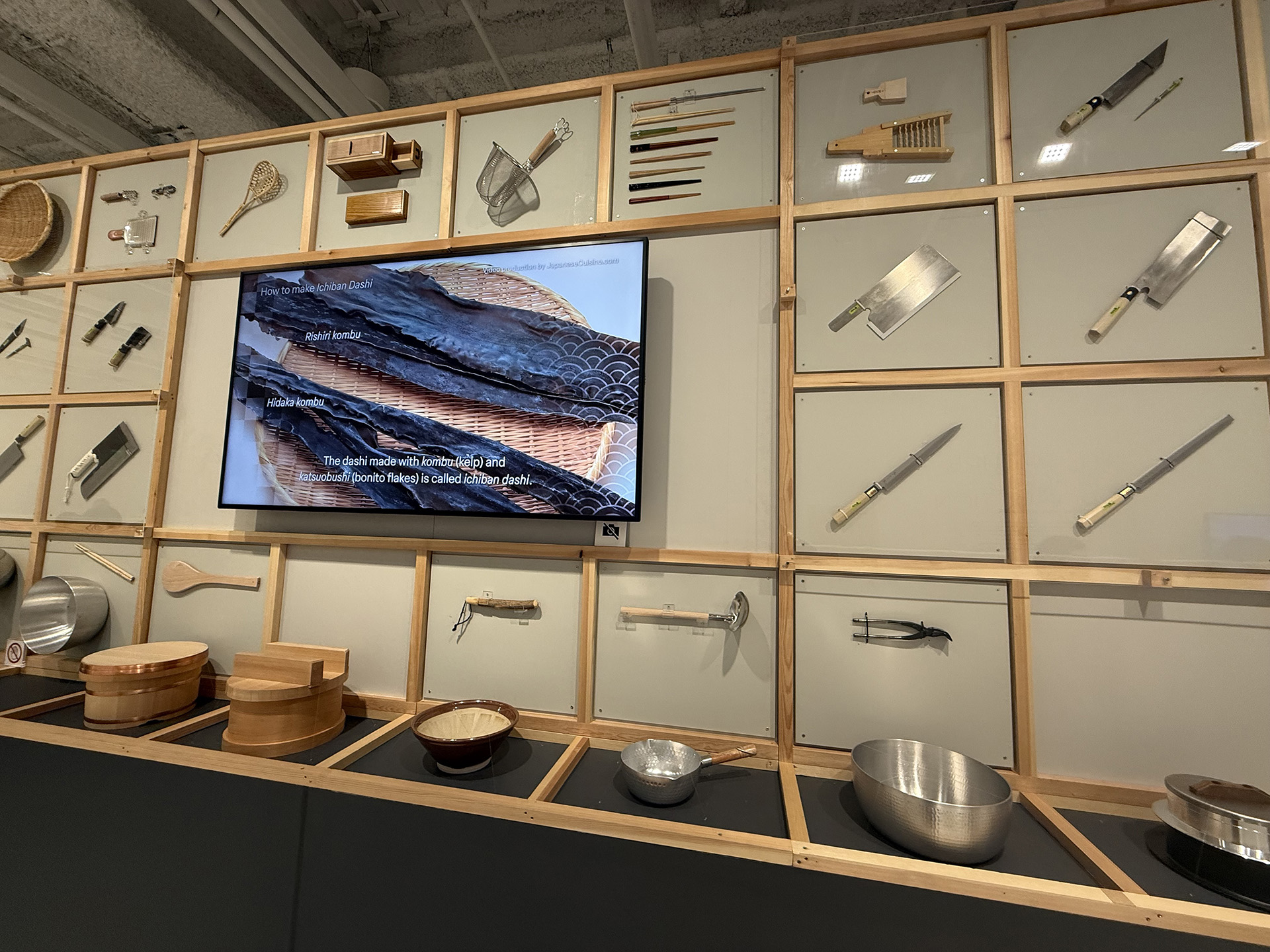 Variety of utensils and a monitor showcasing fish at the Japan House Exhibition