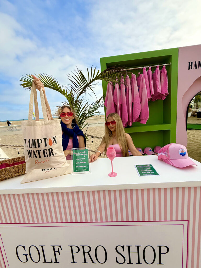 Two women holding up a tote bag at the Golf Pro Shop